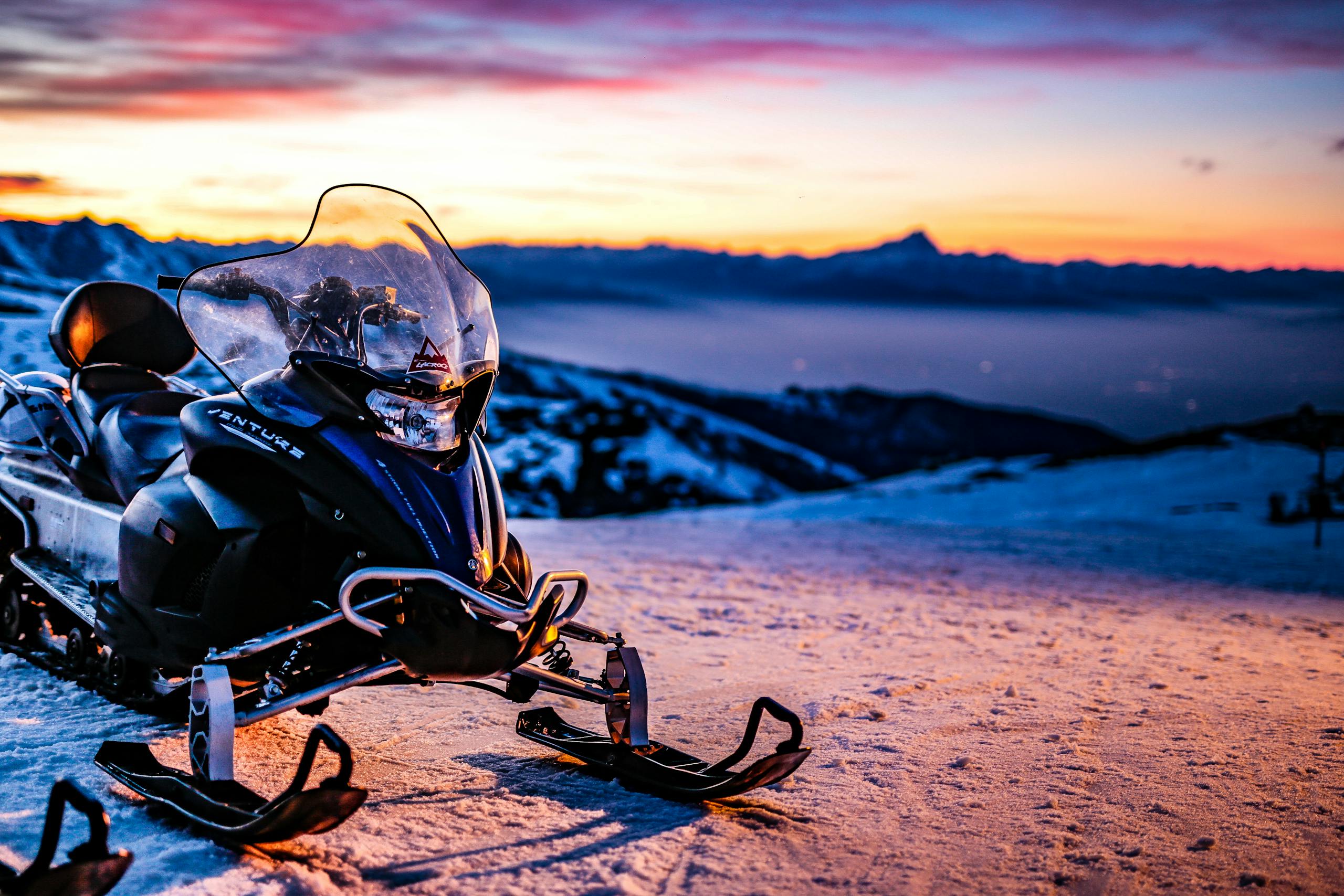 Snowmobile parked on snowy hillside at sunset in Prato Nevoso, Piemonte, creating a vibrant winter scene.